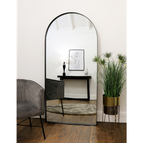Full length arched black large metal mirror leaning against wall