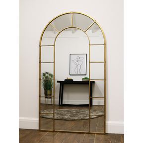 Gold industrial arched full length metal mirror reflecting lounge