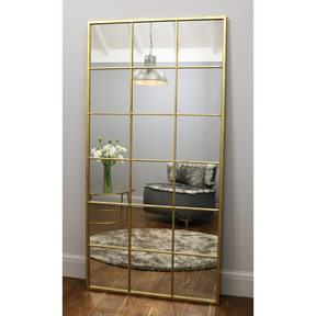 Full length large gold industrial metal window mirror leaning against wall