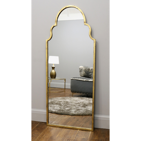 Gold industrial arched large metal mirror leaning against wall
