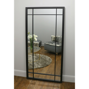 Black industrial full length metal mirror leaning against wall