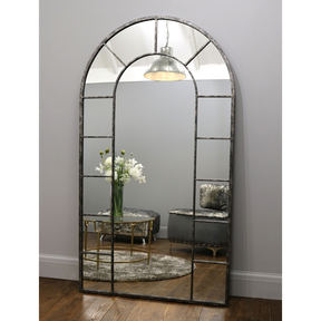 Crushed black industrial arched full length metal mirror with lounge in reflection