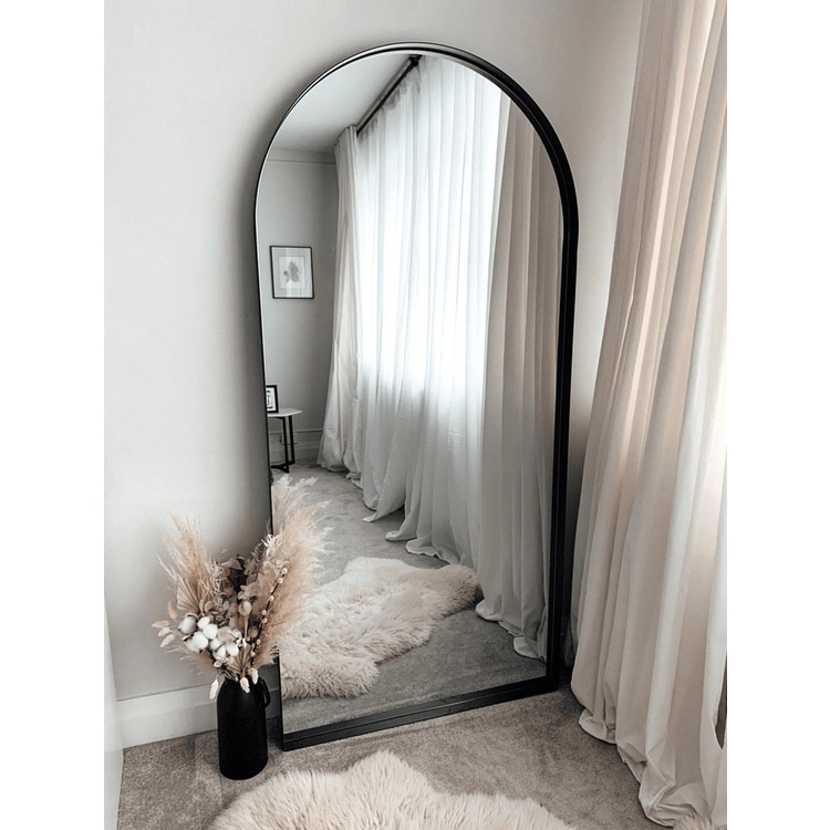 Full length arched black large metal mirror leaning against wall