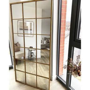 Full length large gold industrial metal window mirror leaning against wall