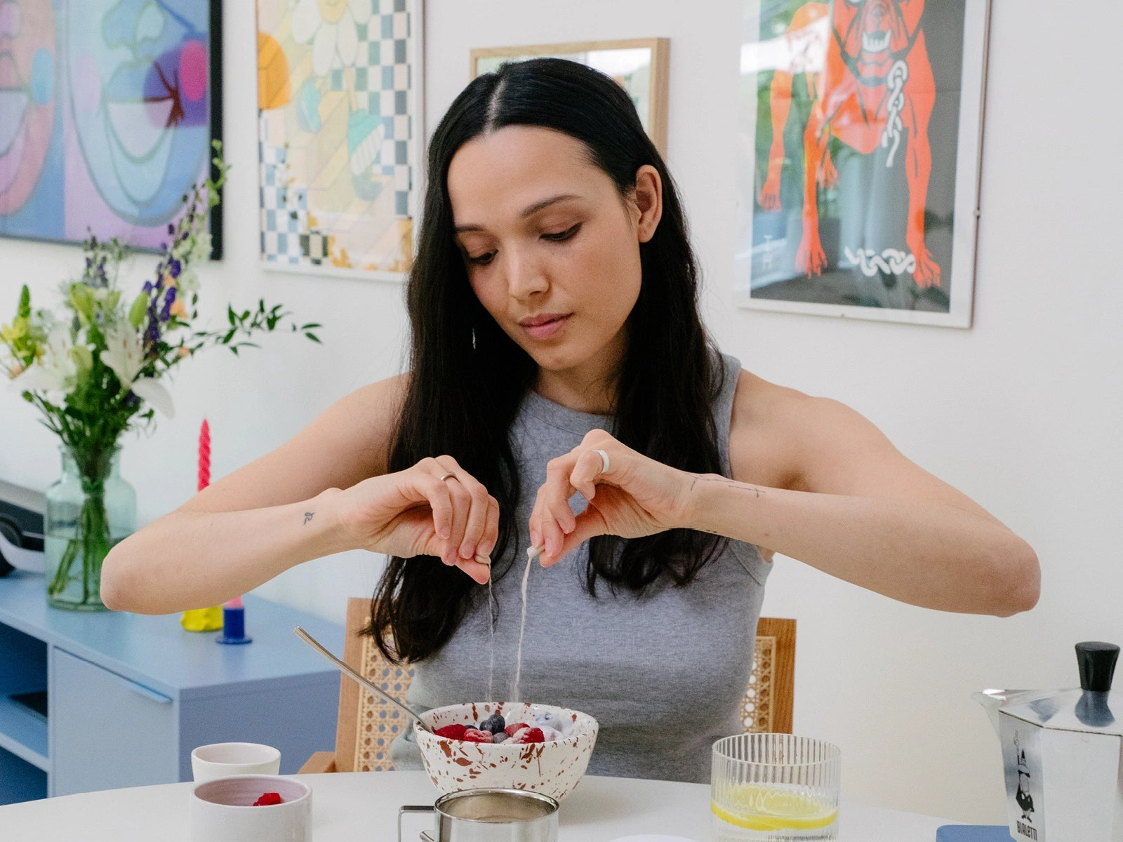 Woman preparing a bowl of berries at a colorful kitchen table.