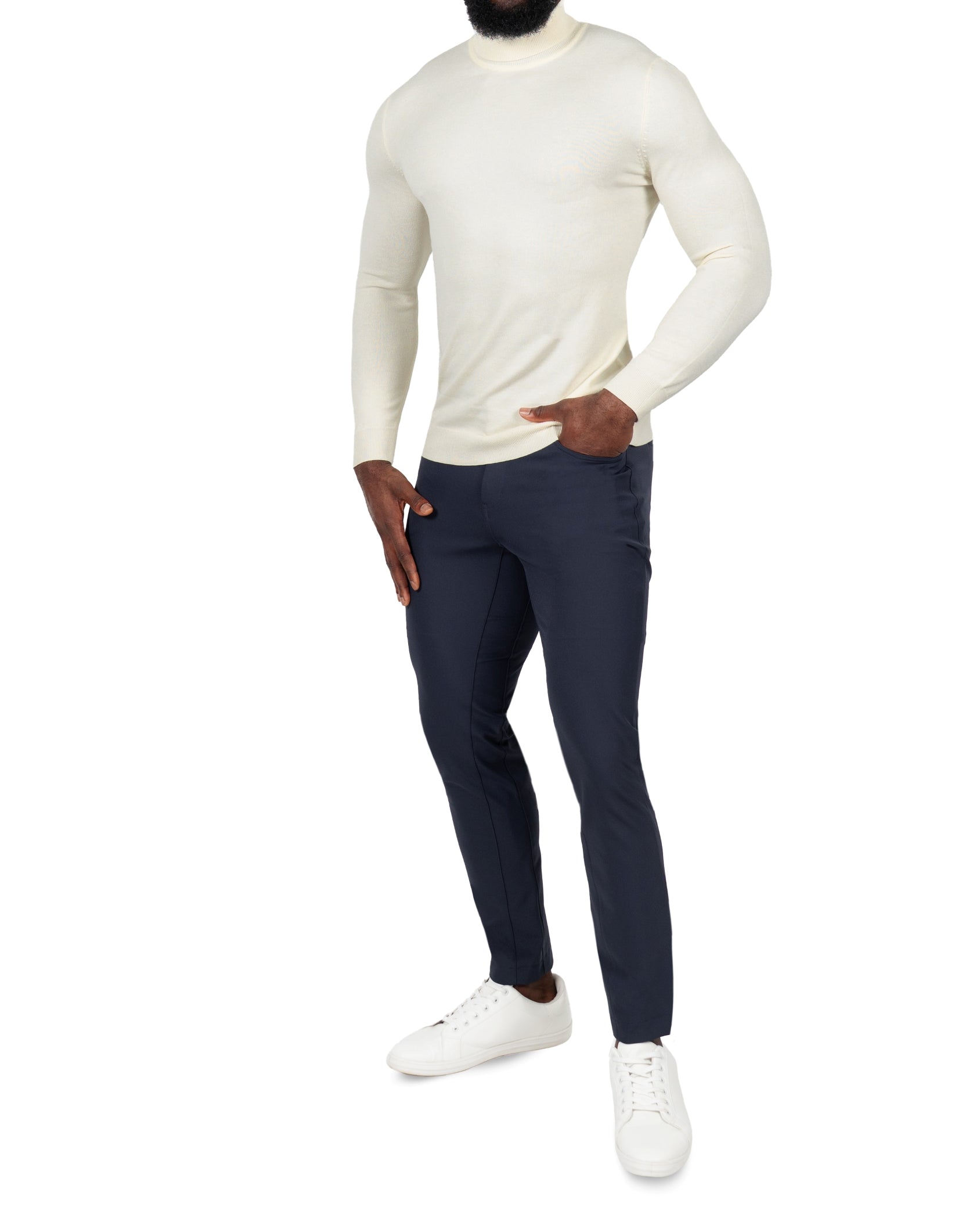 Person wearing a cream sweater and navy pants on a white background