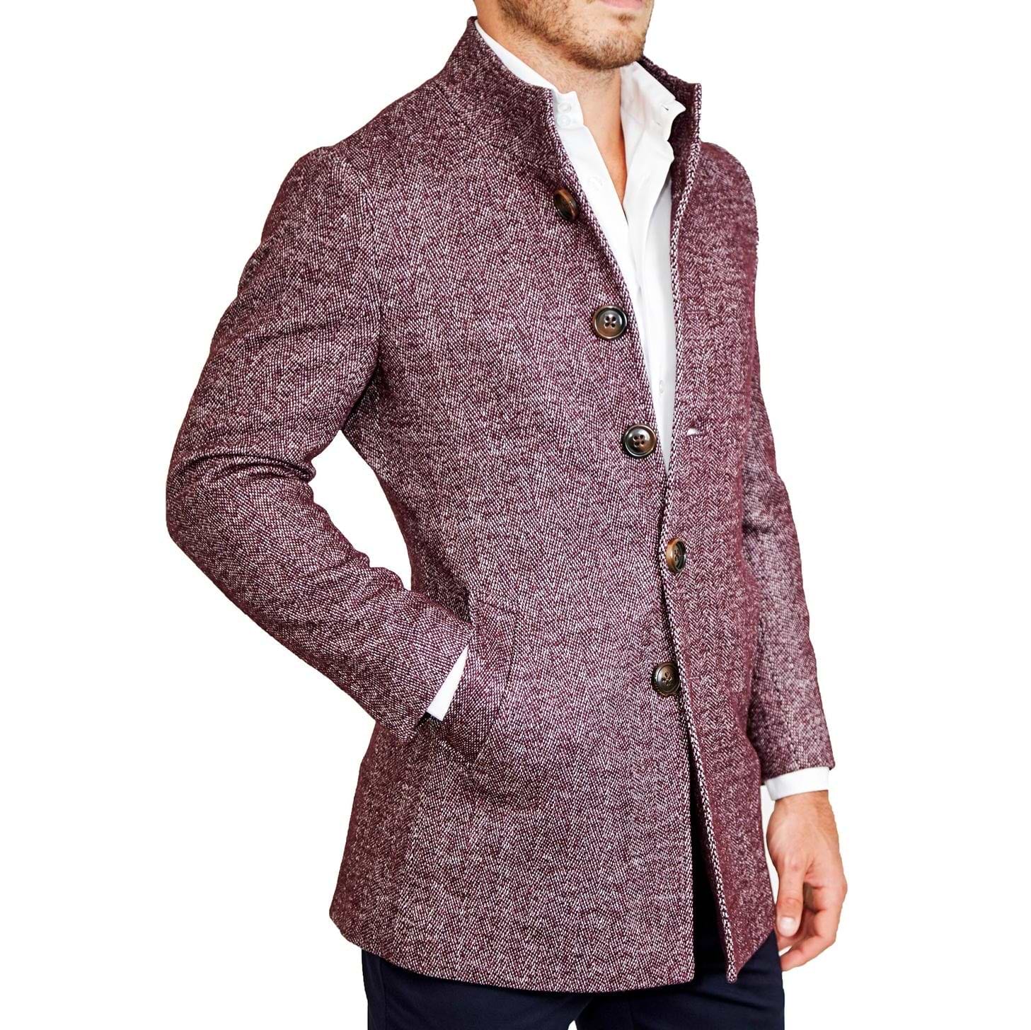 A man wearing a maroon herringbone open button overcoat with a white shirt and blue trousers.