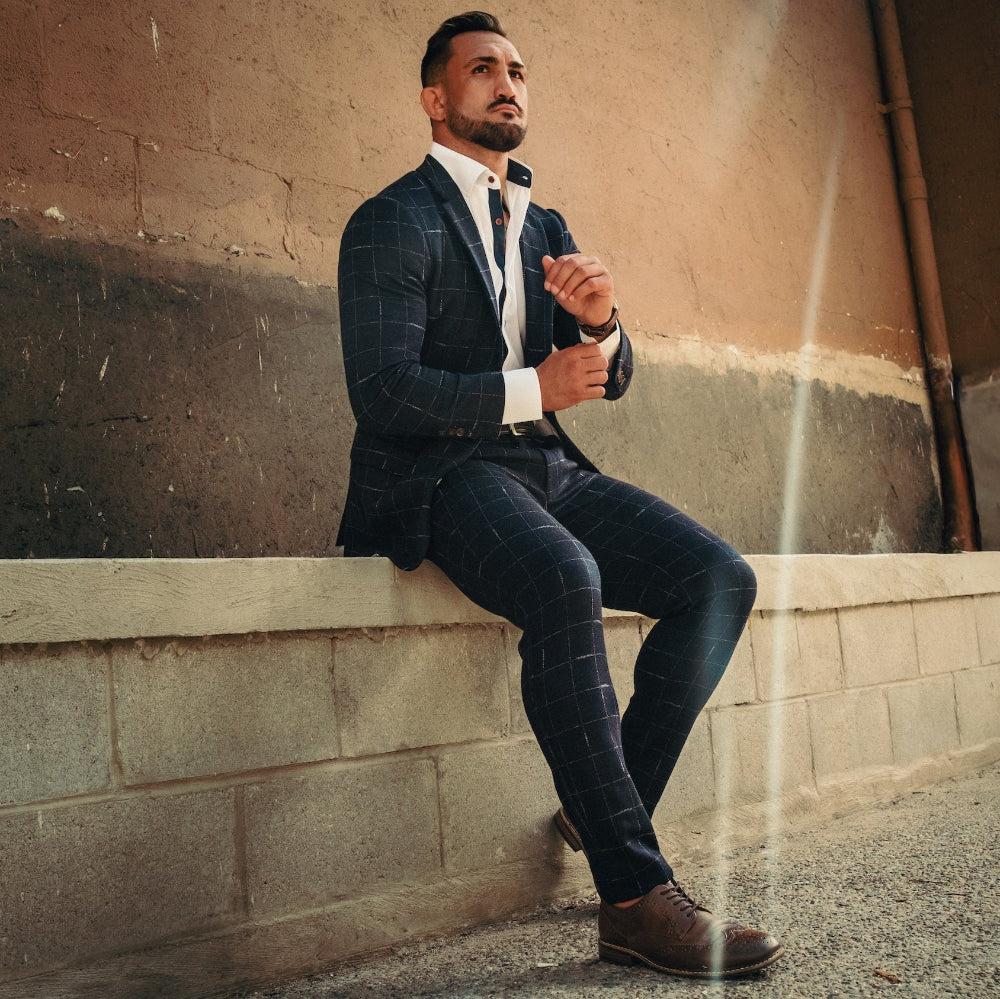 Man in a suit sitting on a ledge against a textured wall