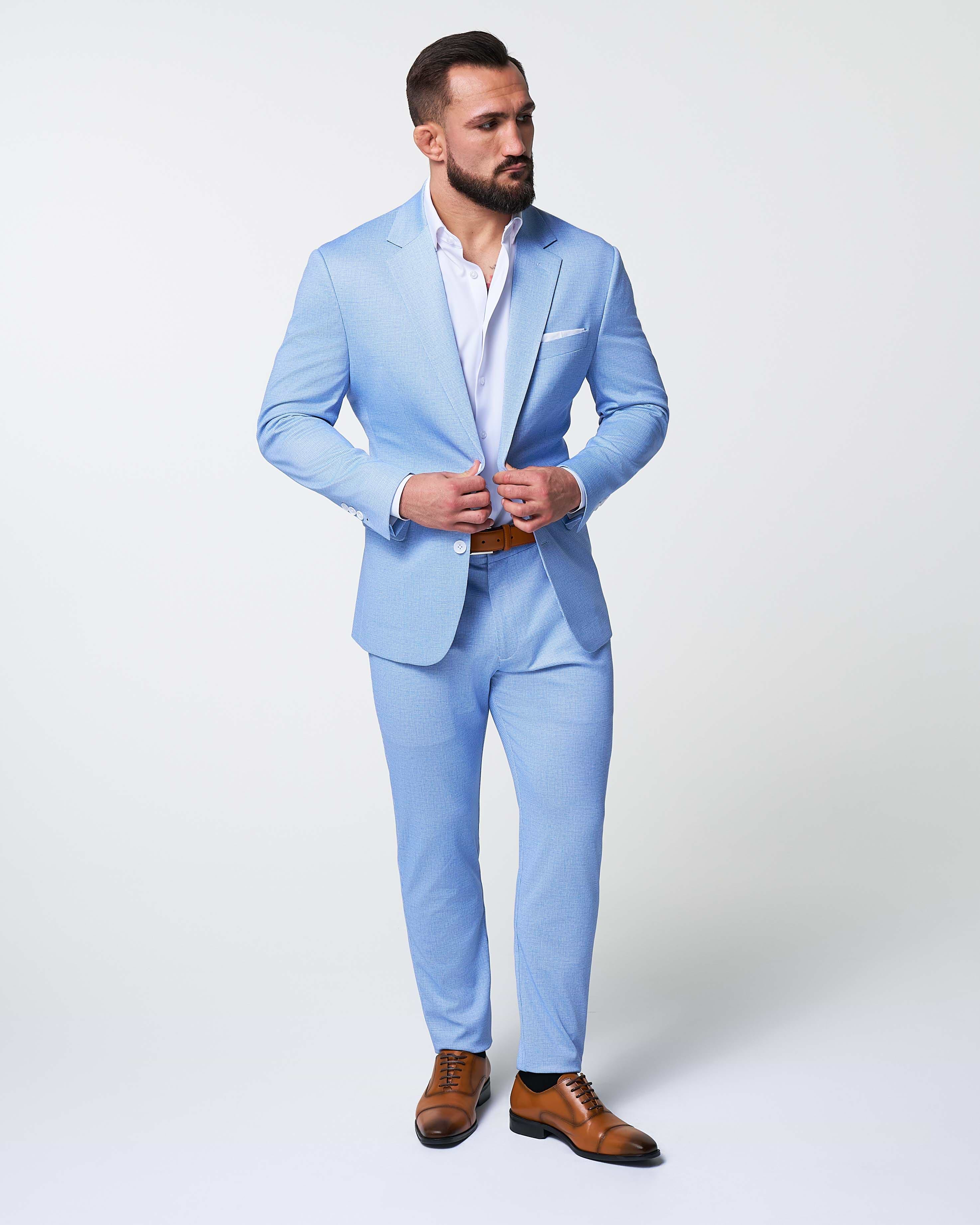 Man wearing a light blue suit with brown shoes on a white background