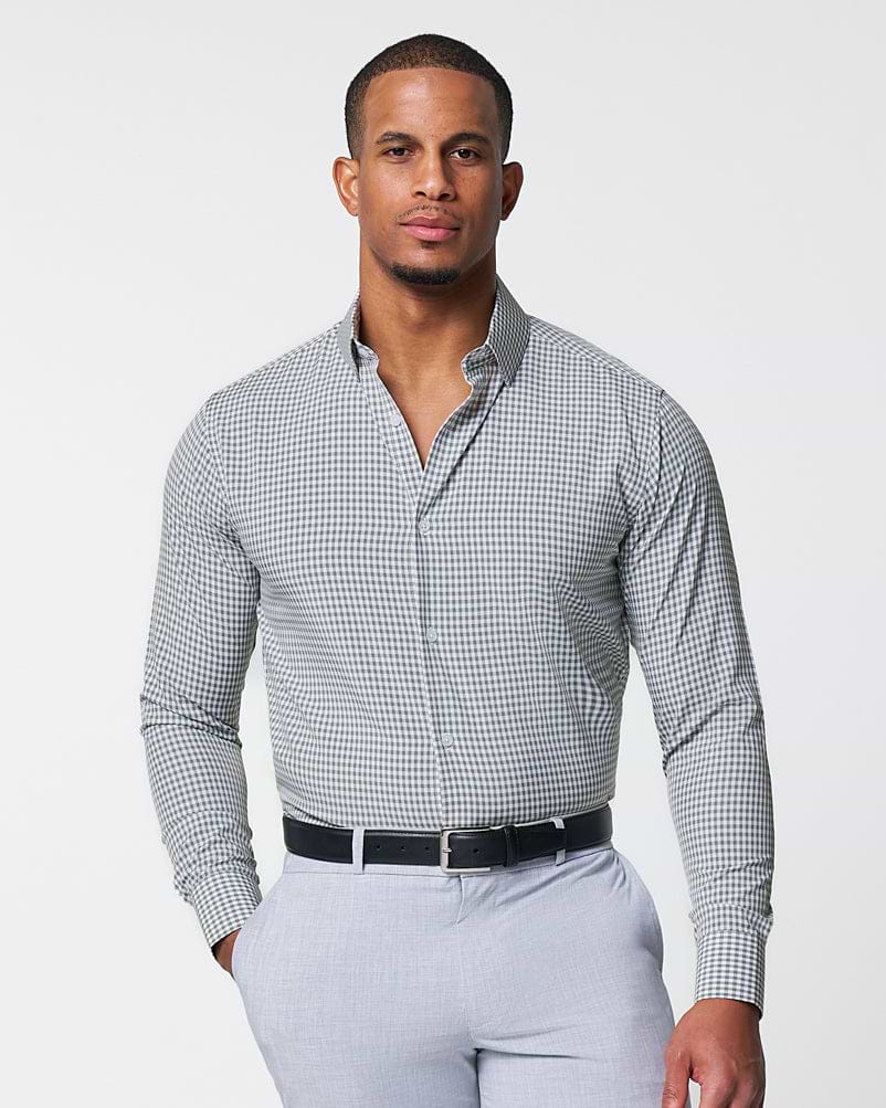 Man wearing a checkered shirt and light gray pants on a white background