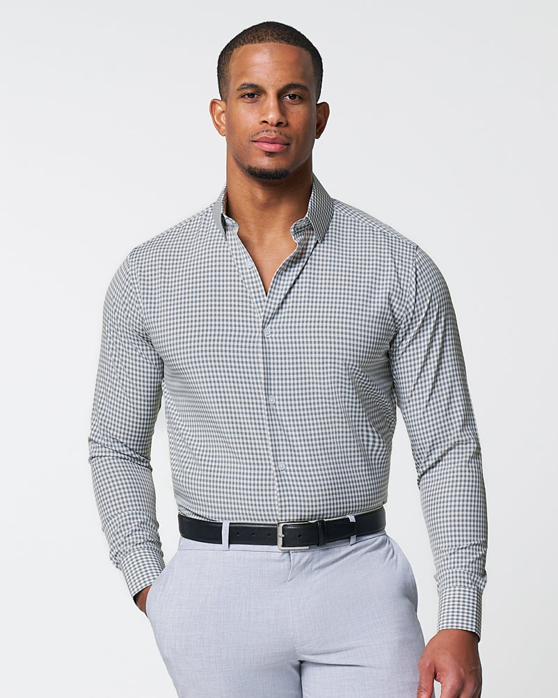 Man wearing a checkered shirt and light gray pants on a white background