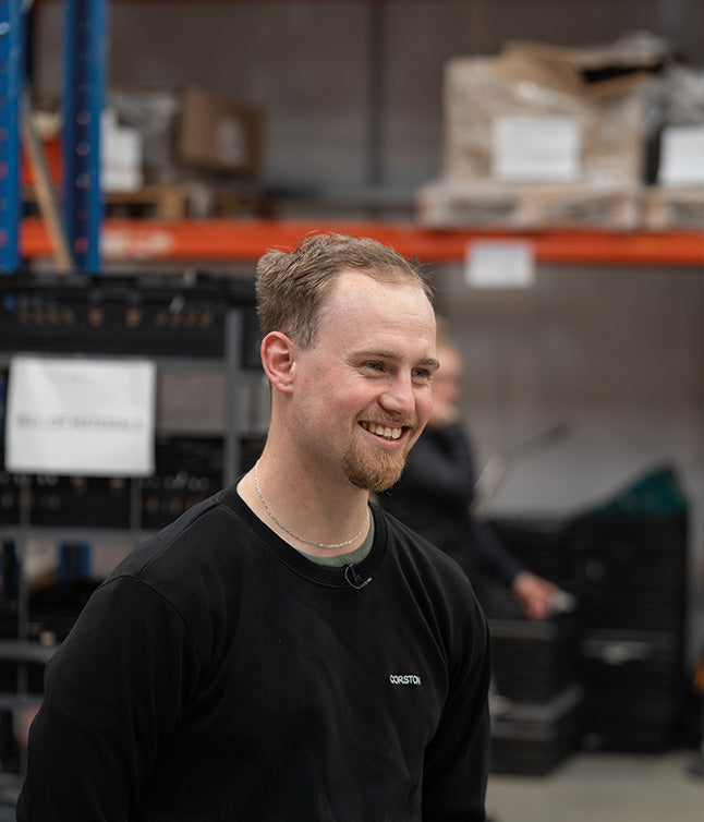 Company employee smiling in front of a blurred warehouse backdrop. 