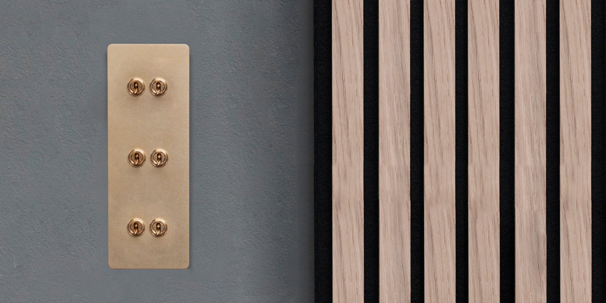 A brass panel with six toggles is mounted on a gray wall, beside vertical wooden slats alternating with black accents.