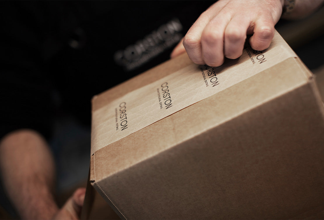 A close-up of a person’s hand gripping a cardboard box labeled 