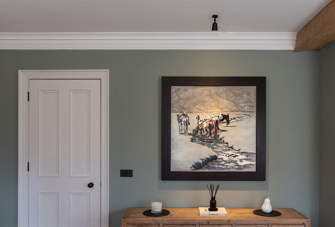 Pivotal bronze 'Baylis Single' ceiling-mounted spotlight, adjusted to illuminate a painting within a living space.