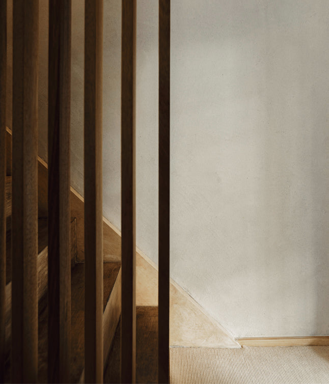 A minimal staircase with wooden railings and a softly lit wall, featuring natural textures and a warm color palette.