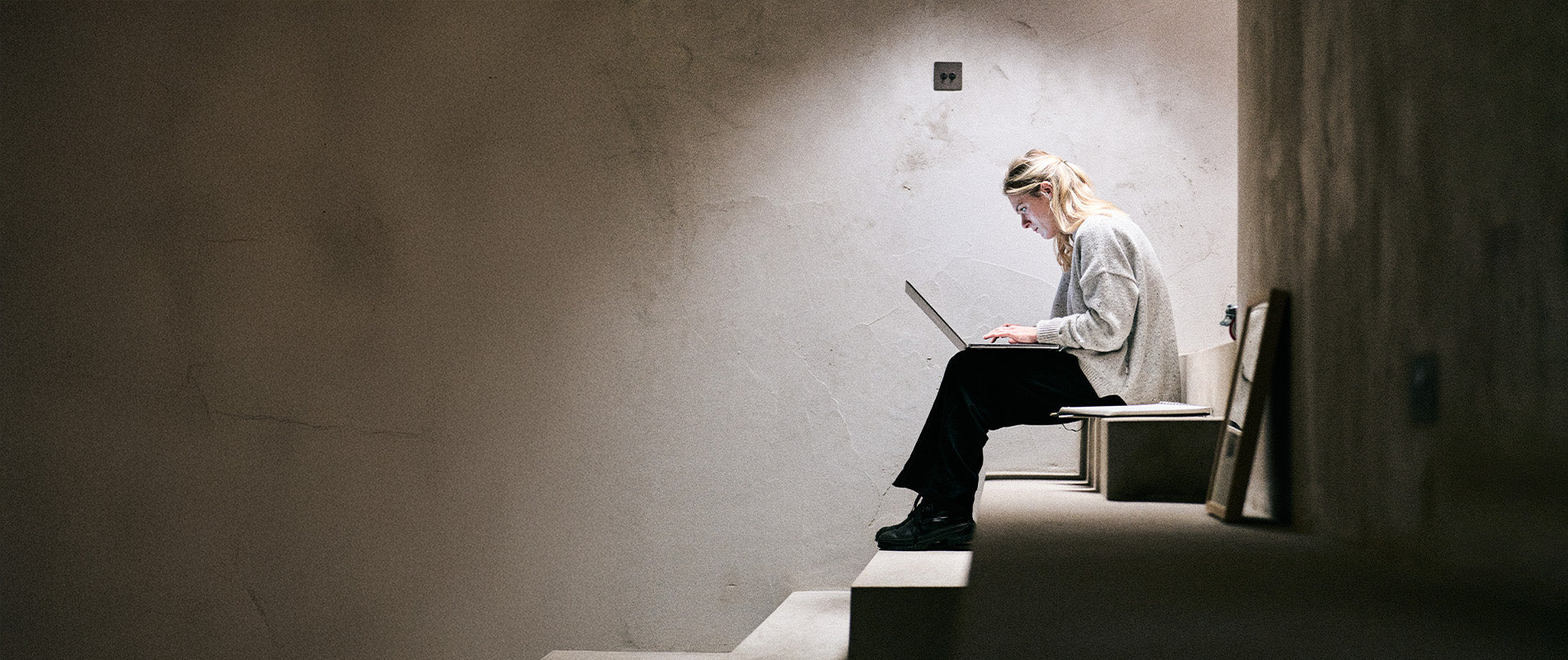 Person working on a laptop whilst sitting on a lit staircase.