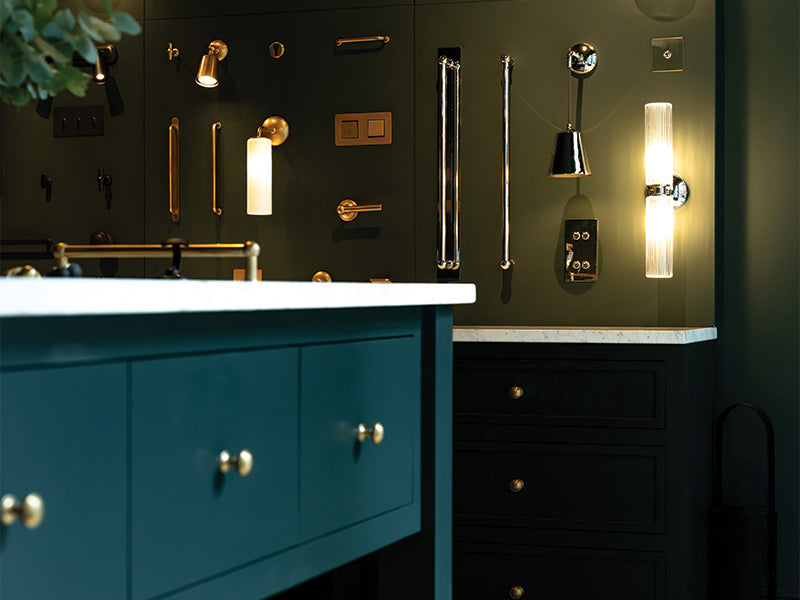 Dark wall showcasing hardware, lighting and light switches. Teal cabinet kitted out with 'Barlow Furniture Knobs'.
