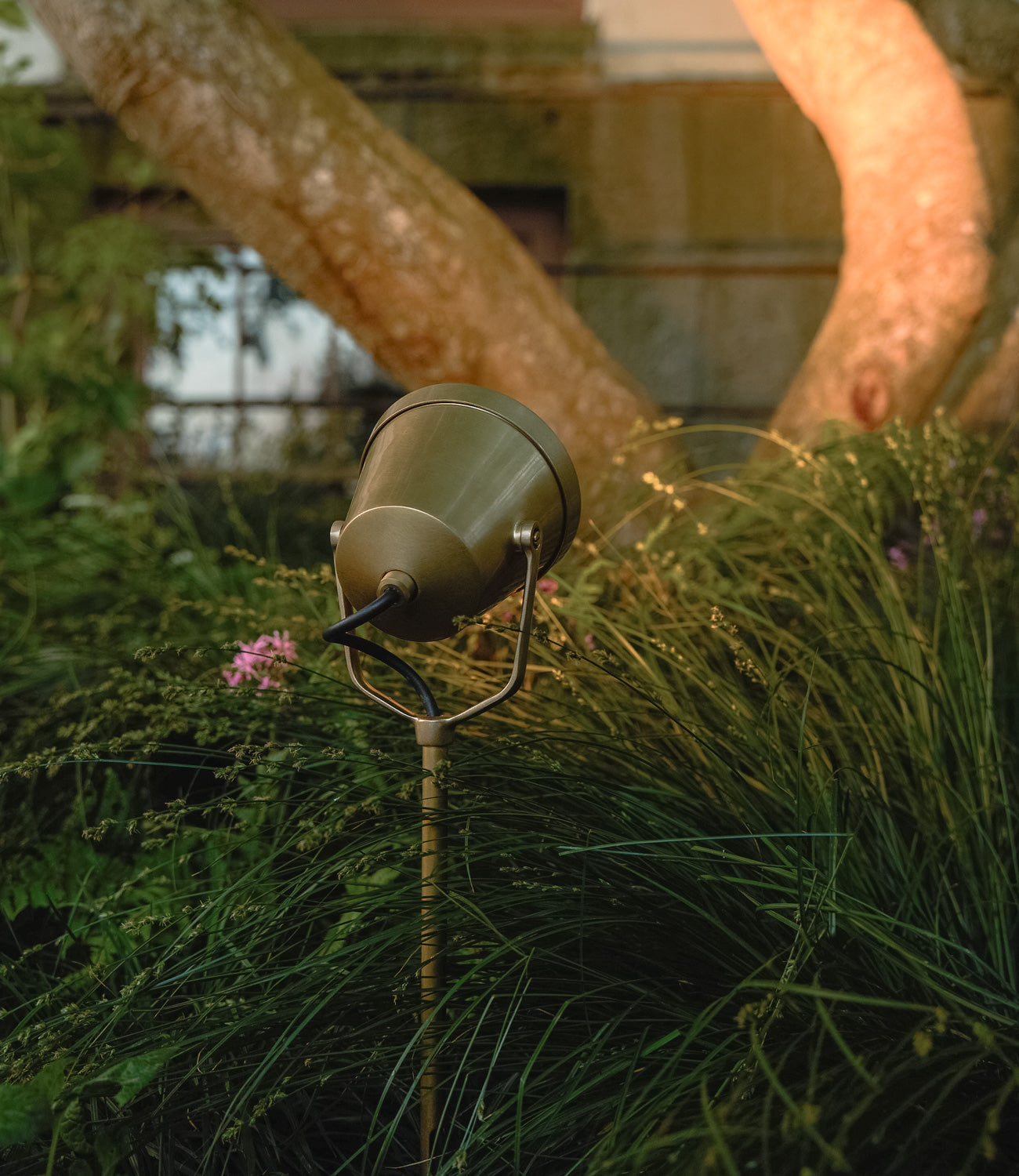 Close-up of a dark bronze 'Ealing Flush Spotlight' illuminating an exterior wall.
