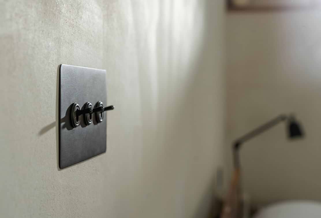 Close-up of a sleek black light switch on a textured wall, with soft natural light creating subtle shadows.