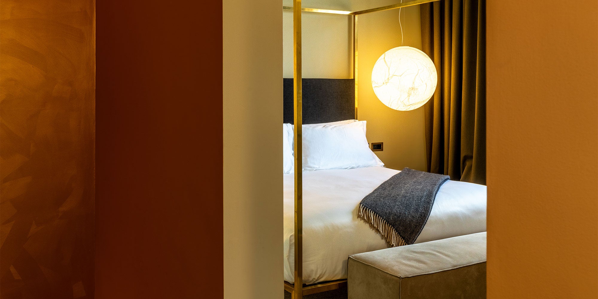 Cozy hotel bedroom featuring a plush bed, elegant lighting, and warm decor, designed for an immersive and artful experience.