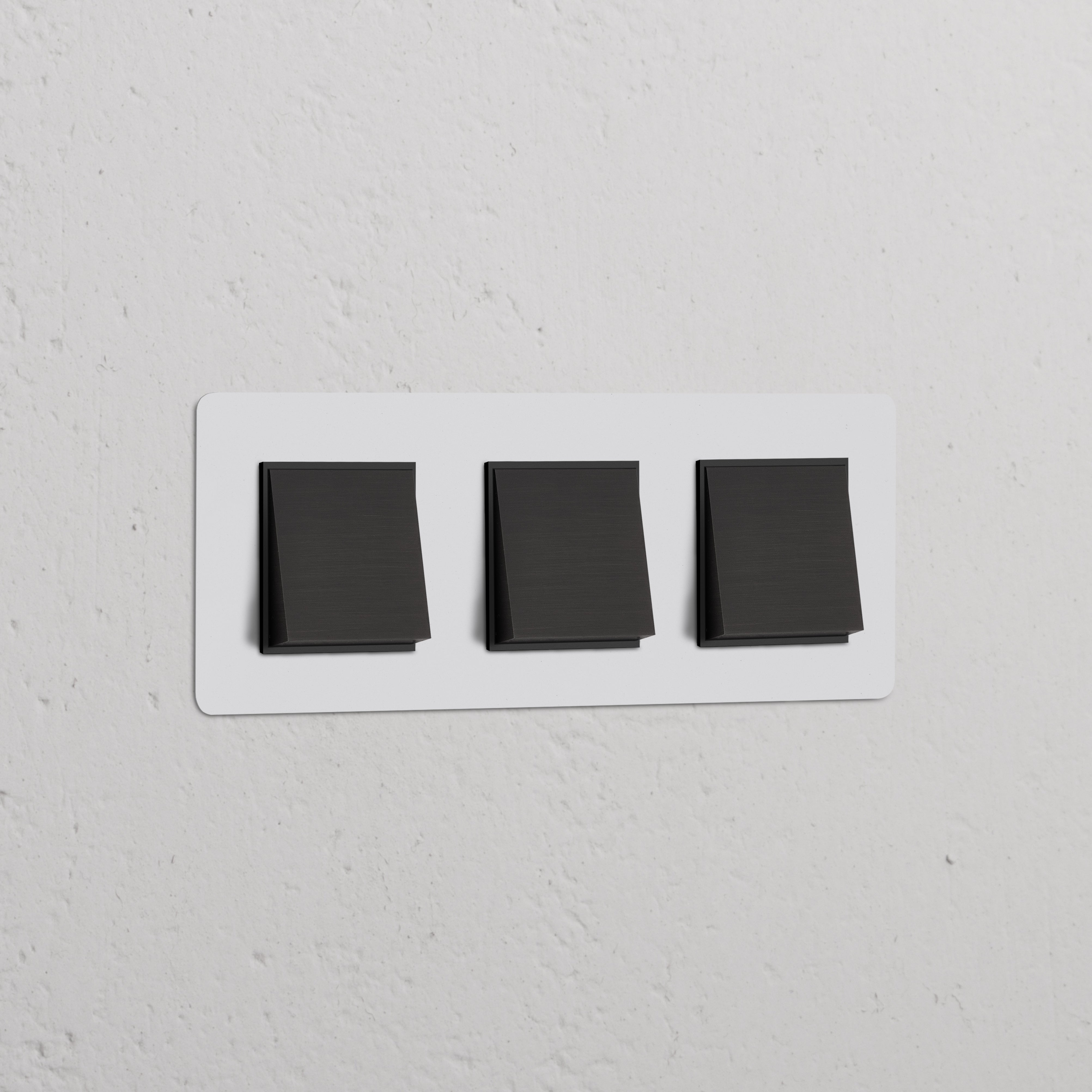 Drievoudige bronzen wissel-wipschakelaars met beschilderbare afdekplaat op een witte wand.