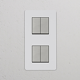 4x Wissel-Wipschakelaar met dubbele verticale afdekplaat in beschilderbaar gepolijst nikkel wit, tegen muurfond.