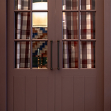 Harper Deurtrekker 320mm - Bronzen greep op houten deuren met glaspanelen, met geblokte gordijnen en een lamp erachter.