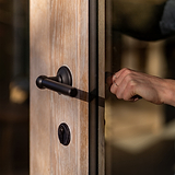Accessoire Canning Rosace à Clé de Serrure en bronze sur une porte en bois avec poignée noire.