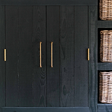 Sycamore Poignée de Meuble 224mm - Laiton Poignée de traction d'armoire moyenne en laiton ancien contre une surface en bois.