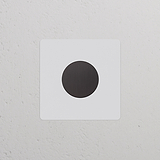 Le Variateur Peignable en Bronze présente un design de plaque simple, monté sur un mur blanc texturé.