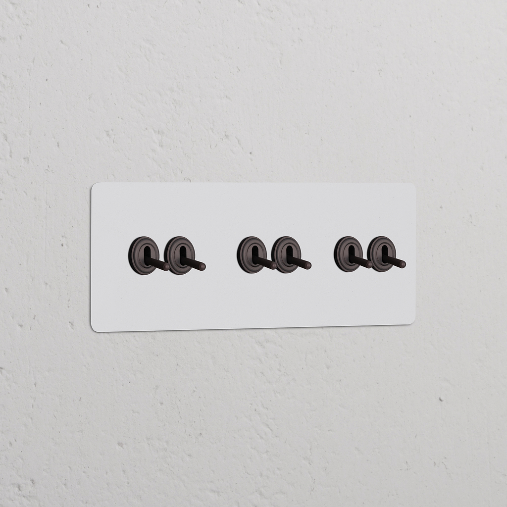 Interrupteur Peignable en bronze VV à Levier x6 sur plaque triple, monté sur un mur texturé.