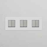 Interrupteur VV Carré x6 (Plaque Triple) - Nickel Poli Peignable Insert Blanc interrupteurs sur un mur texturé blanc.