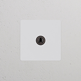 Interrupteur à levier Peignable en bronze (Plaque Simple) sur mur blanc, faisant partie de la collection Interrupteurs & Variateurs Simple.