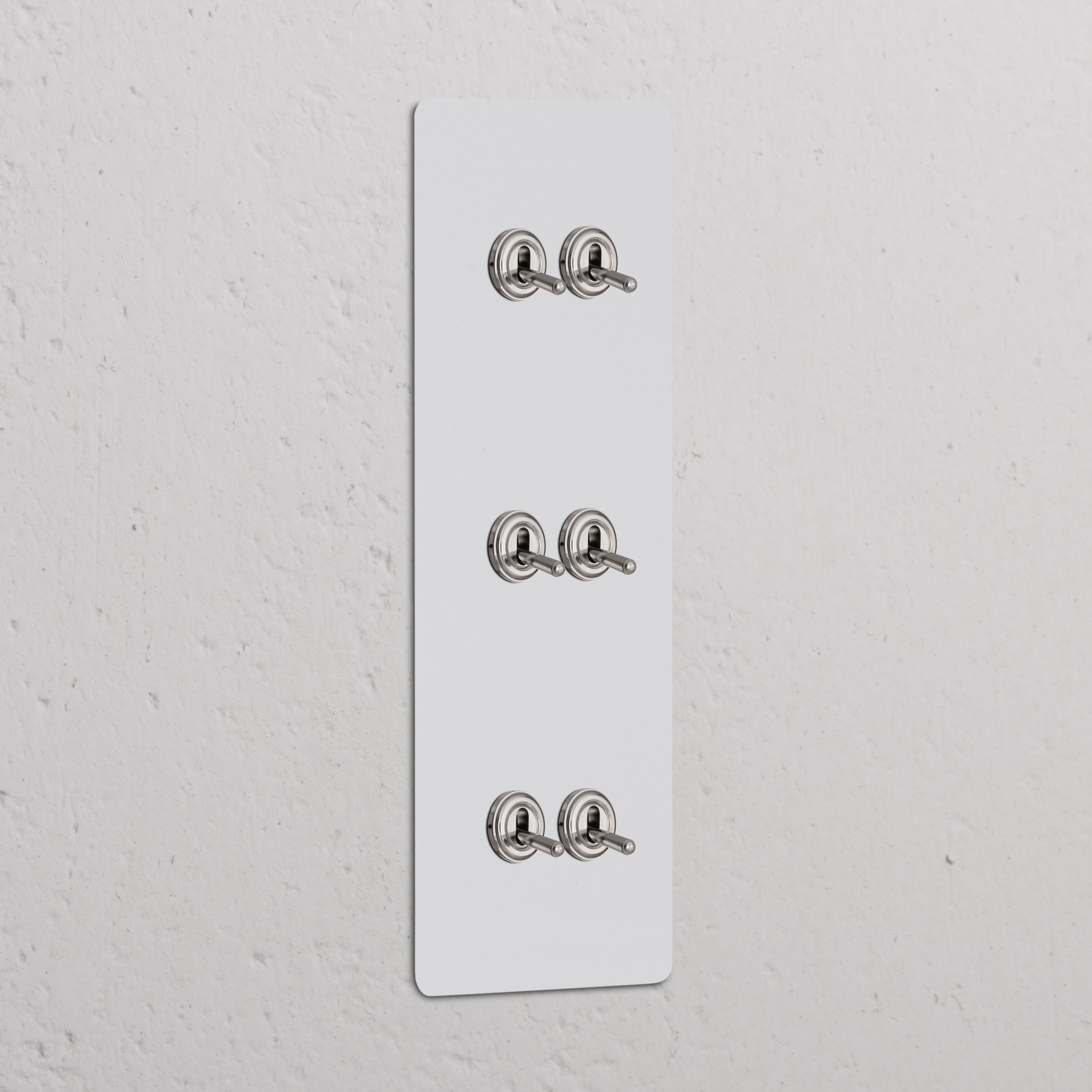 Panneau triple Peignable Nickel Poli avec six Interrupteur VV à Levier x6 Interrupteurs verticaux sur un mur texturé blanc.