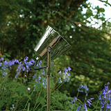 Cambridge Gartenleuchte Outdoorleuchte aus poliertem Nickel steht im Garten zwischen blühenden Blumen und Grün.