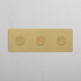 Dreifachrahmen mit 3x Mehrpunkt-Dimmerschalter in Antik-Messing, montiert an einer weißen Wand.