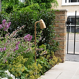 Ealing Wegestrahler – Outdoorbeleuchtung in antikem Messing, beleuchteter Gartenweg neben Ziegelpfeiler.