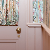 Warwick Badverriegelung Rosettengarnitur in Antikes Messing auf einer rosa Tür, passend zu leuchtend marmorierten Vorhängen.