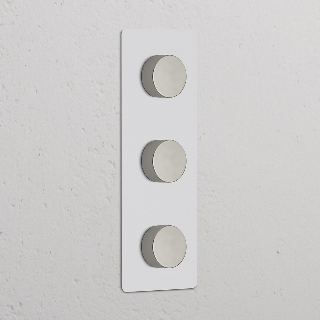 Vertikaler Dreifachrahmen mit 3x Dimmschalter, lackierbar, poliertes Nickel auf strukturiertem Hintergrund.