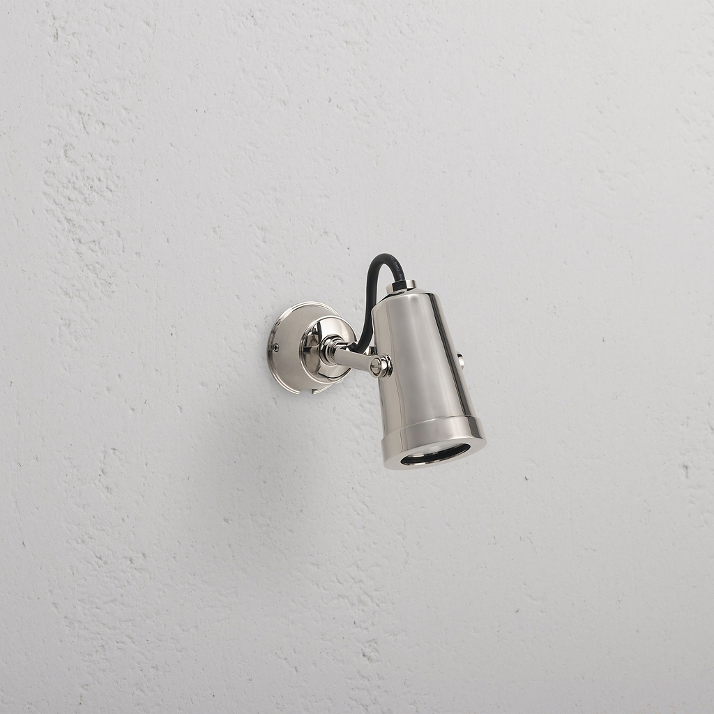 Cambridge Wandstrahler 24V Outdoorstrahler in poliertem Nickel, wandmontiert mit schwarzem Kabel, nach unten gerichtet.