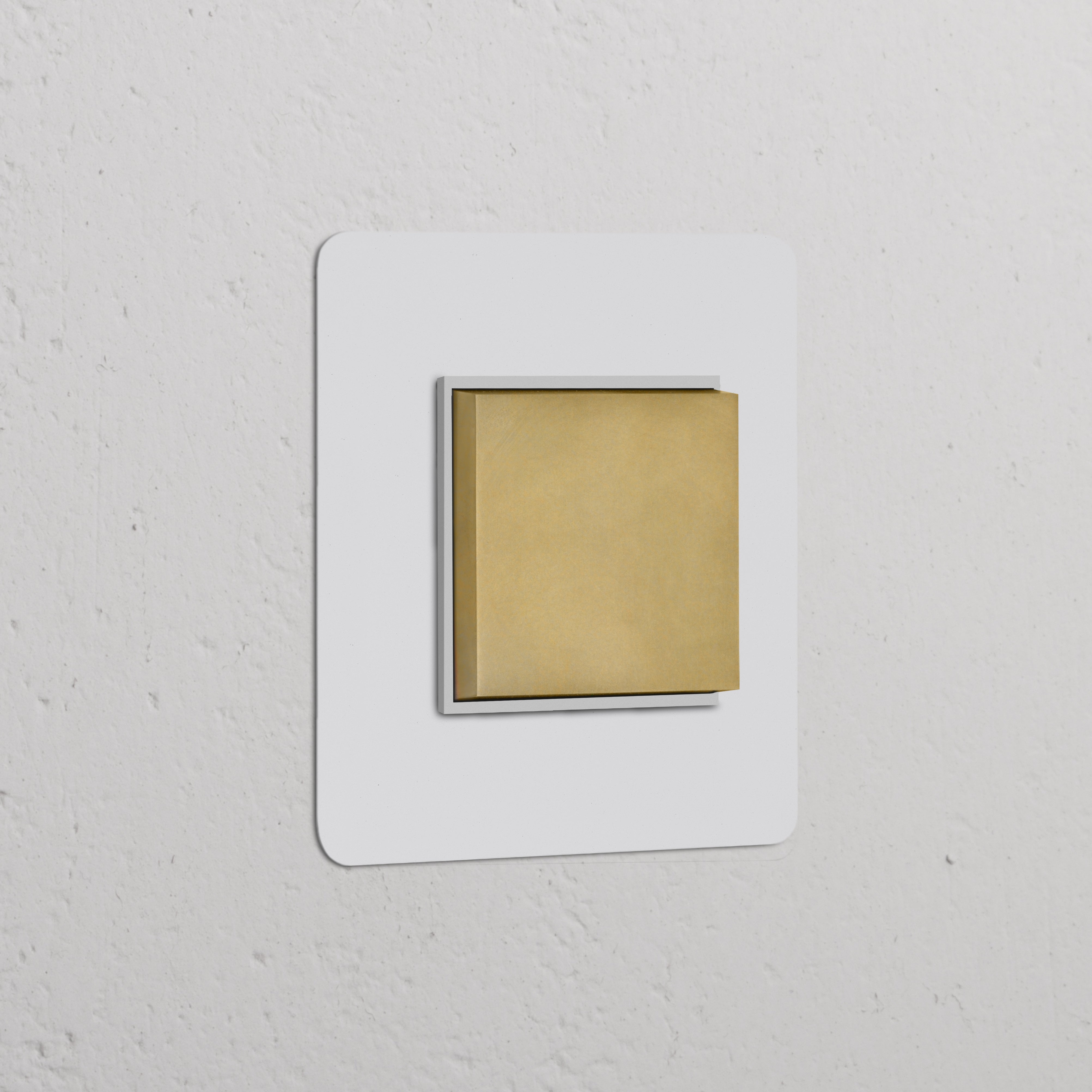 Wandschalter mit zentrierter Wippe in einem einfachen Rahmen, lackierbares Finish in Antikmessing und Weiß, auf einer strukturierten Wand.