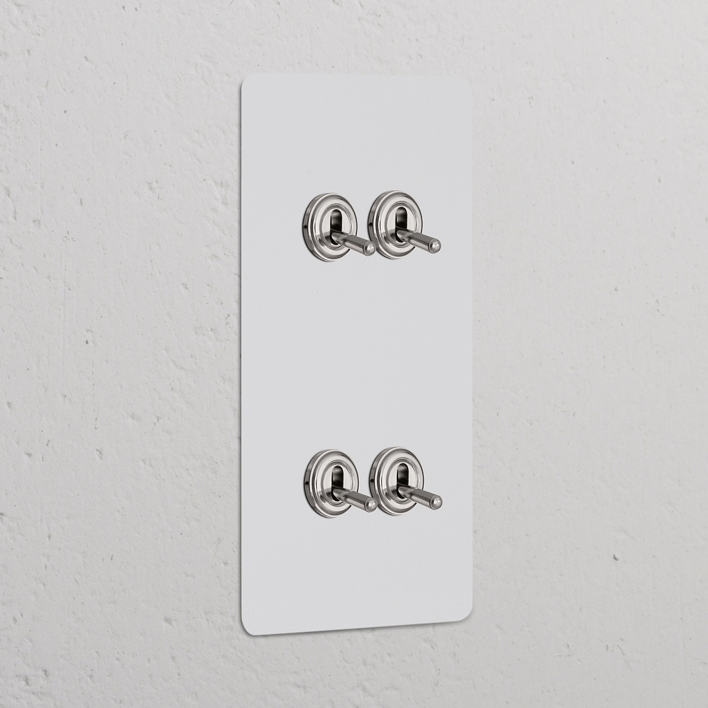 Vertikaler Zweifachrahmen mit 4x Kipphebelschalter, lackierbar, poliertes Nickel, an einer Wand montiert.
