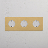 SchuKo Steckdosen (Typ F) im dreifachen Rahmen, Antikmessing und Weiß, montiert an einer weißen Wand.