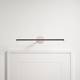 Die wandmontierte Taylor Bilderleuchte 400 mm in poliertem Nickel beleuchtet einen Bilderrahmen an einer weißen Wand.