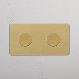 Zweifachrahmen mit 2x Mehrpunkt-Dimmerschalter in antikem Messing, montiert an einer weißen Wand.