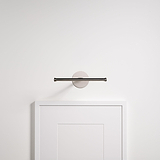 Taylor Bilderleuchte 220 mm in poliertem Nickel, beleuchtet ein gerahmtes Bild an einer minimalistischen weißen Wand.