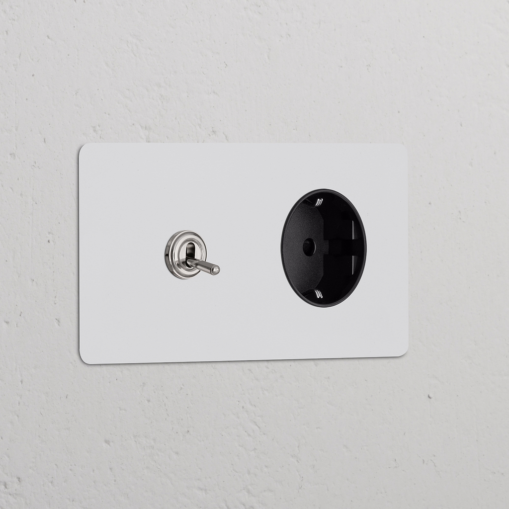 Marco doble de pared con interruptor de palanca y base Schuko tipo F; pintable, acabado níquel, inserto negro.
