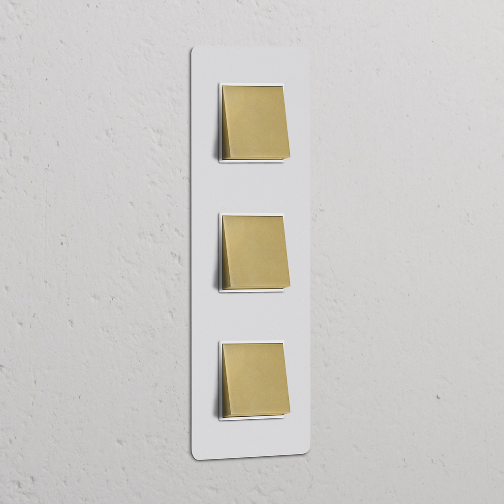 Juego de interruptores basculantes triples verticales en latón antiguo pintable con inserto blanco, para control de iluminación.