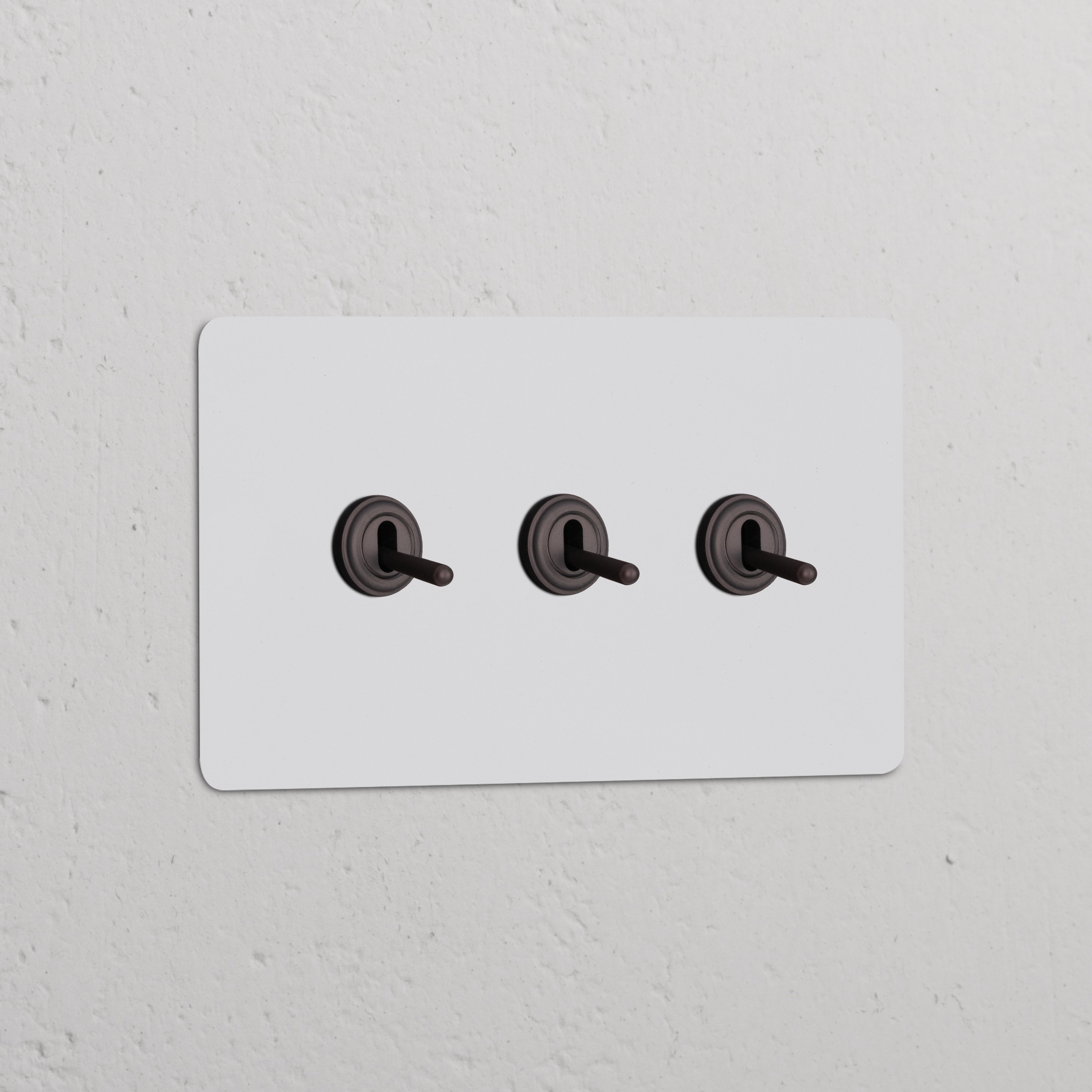 Interruptor conmutador de palanca x3 en marco doble pintable y bronce sobre pared blanca, elegante y funcional.